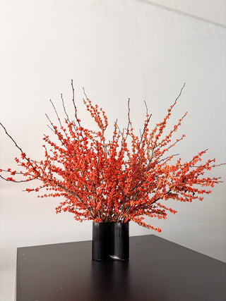 Orange berry branches in a black vase