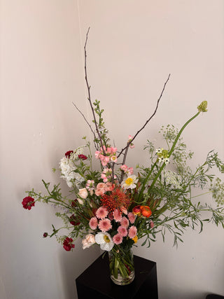 Wildflowers arrangement in glass vase on a black pedestal