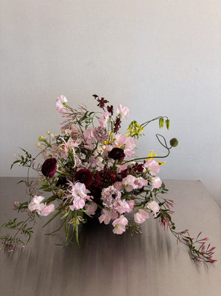 Floral arrangement with pink and burgundy flowers on a neutral background