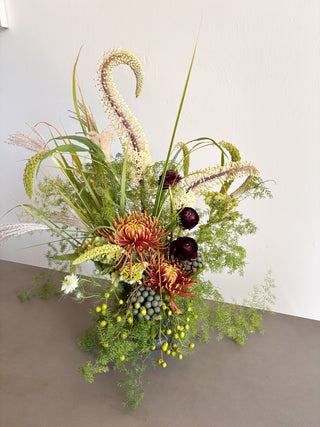 Floral arrangement with textured greenery on a neutral background