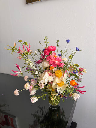 Bouquet of colorful peonies and wild flowers on a gray surface