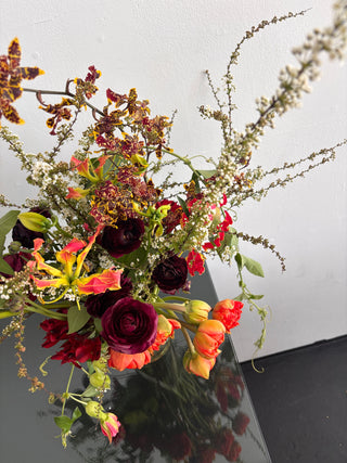 Bouquet of flowers with red, orange, and green colors against a neutral background
