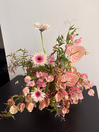 Bouquet of pink and white flowers on a reflective surface with a light gray background