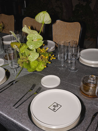 Dining table setting with plates, glasses, and a decorative plant.