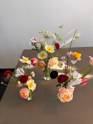 Clear glass bud vases with peach garden roses and wildflowers 