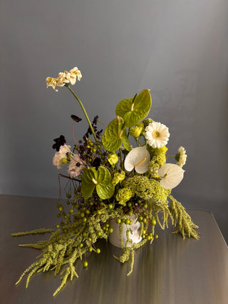 Floral arrangement with greenery and white flowers on a dark background