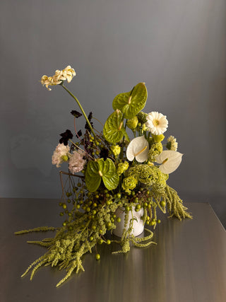Bouquet of white and green flowers with greenery against a dark background
