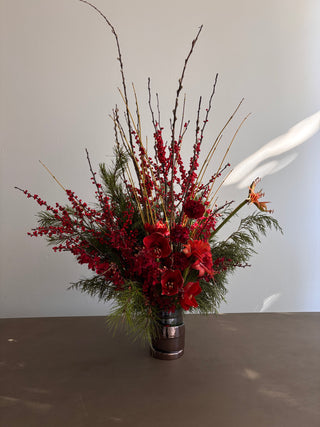 Decorative floral arrangement with red flowers and greenery attached to a metallic surface.