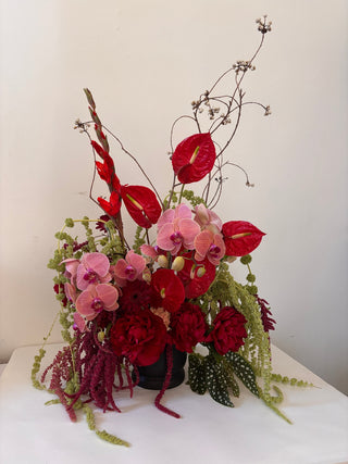 Bouquet of red and pink flowers with greenery on a white background
