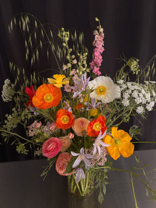Colorful bouquet of flowers in a clear vase against a black background