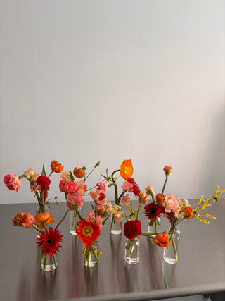 Decorative floral arrangement with red, orange, and pink flowers on a plain background