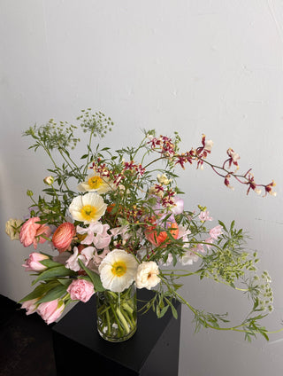 Bouquet of flowers in a clear vase on a light gray background