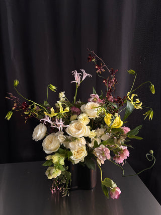Floral arrangement with white, yellow, and pink flowers on a black background