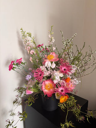 Colorful flower arrangement in a black vase on a light gray background