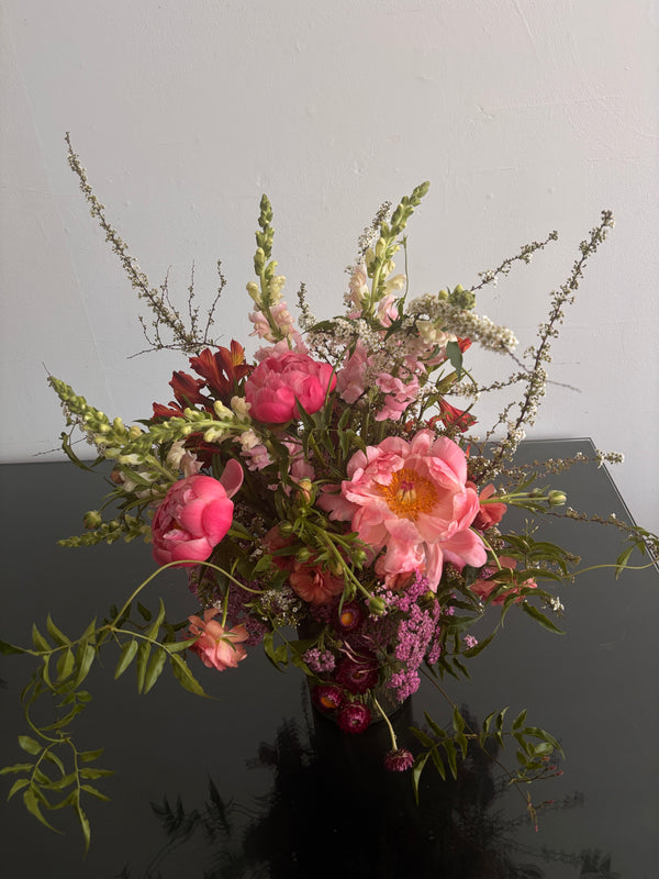 Bouquet of pink peonies and green flowers against a gray background