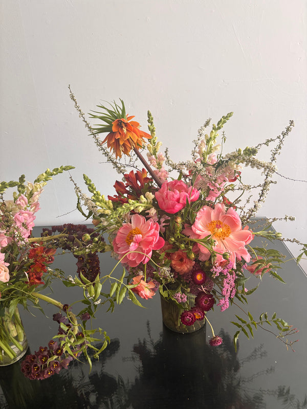 Colorful floral arrangement with pink, orange, and green flowers against a neutral background