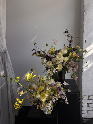 Floral arrangement with white, yellow, and purple flowers on a plain background