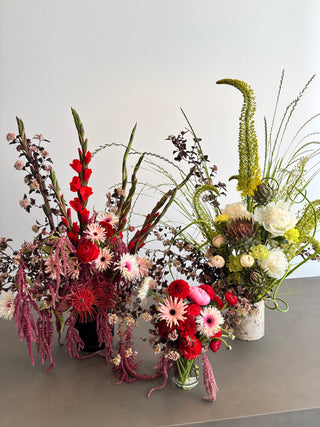 Colorful floral arrangement with red, pink, and green flowers on a light gray background