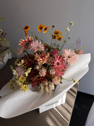 Bouquet of pink flowers wrapped in white paper on a gray surface