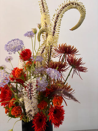 Bouquet of red, orange, and purple flowers with a gold swan on a white background