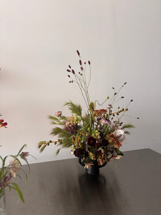 Floral arrangement in a vase on a dark surface with a light gray background