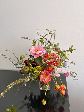 Bouquet of colorful flowers on a reflective surface with a white wall background